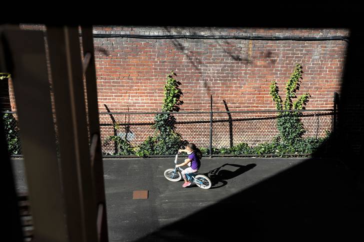 A young child rides her bicycle in an empty courtyard on Manhattan's west side in New York.